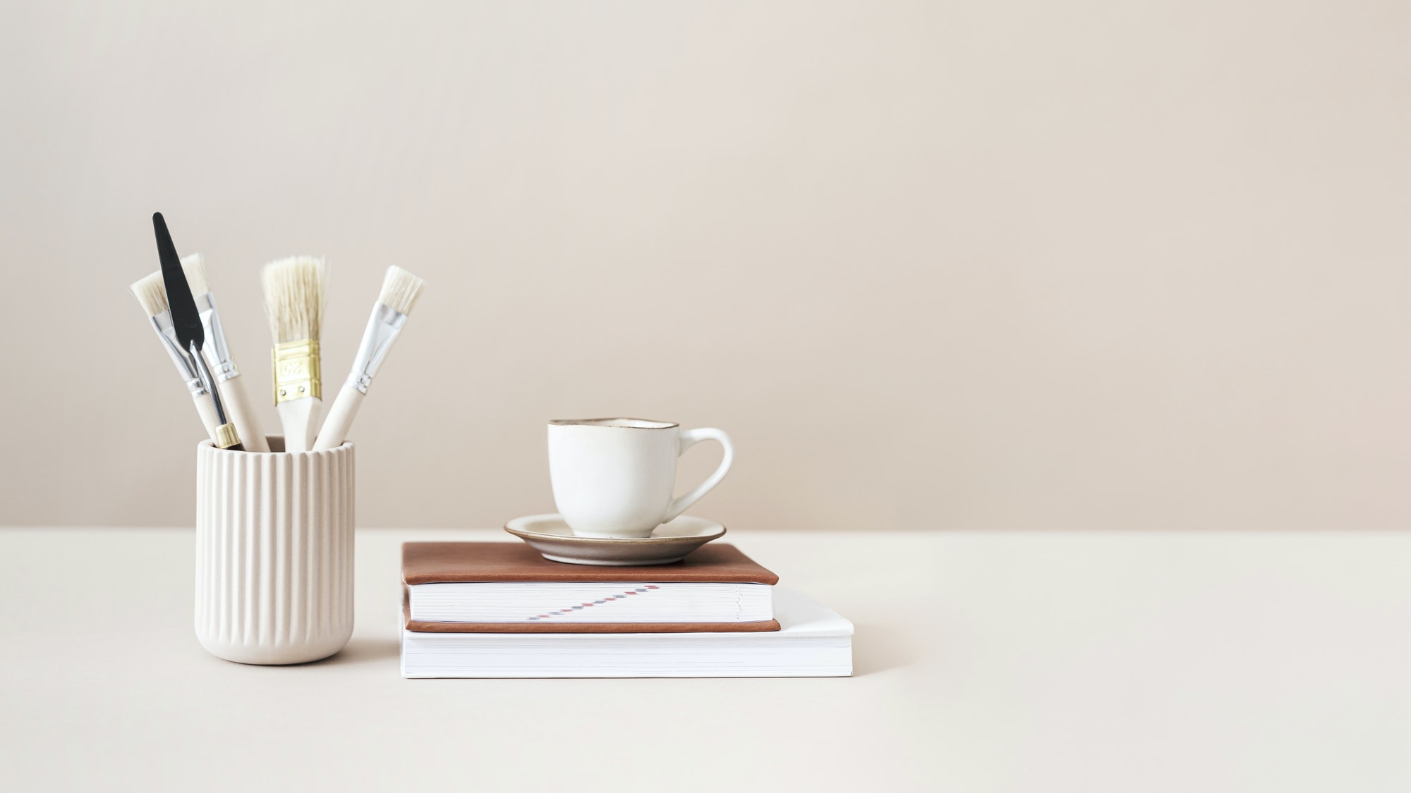 Paintbrushes and cup on top of books